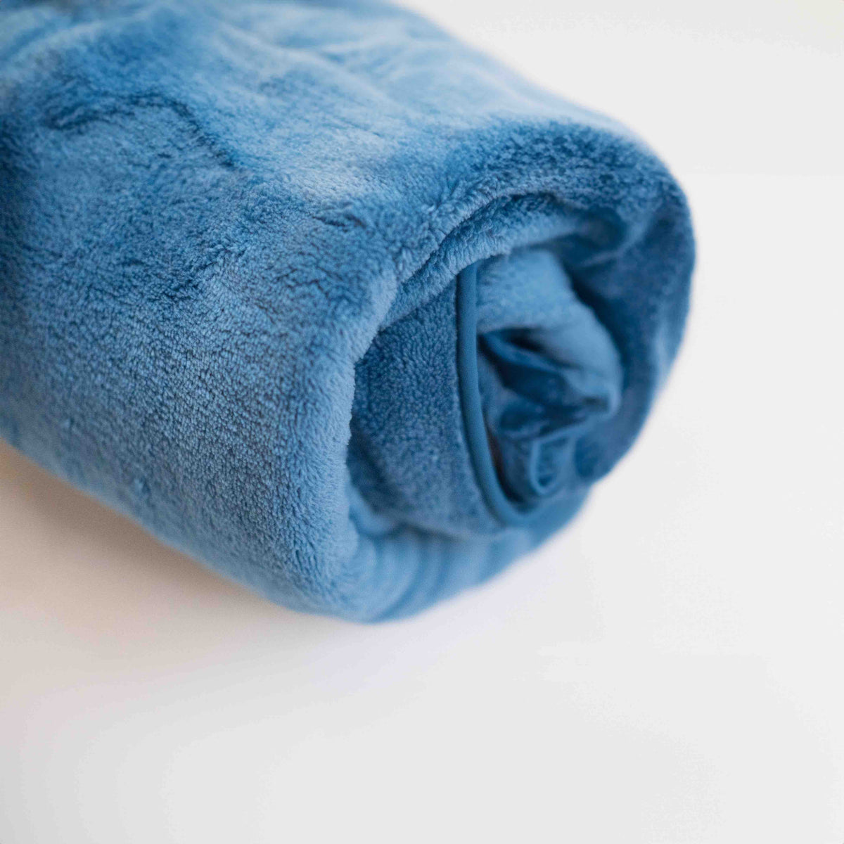 Der blaue Ocean Breeze Dog Towel Robe, zu einem kompakten Bündel gerollt.
